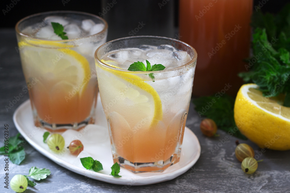 Gooseberry lemonade with mint and ice, a bottle of water and a bottle of gooseberry syrup on a concrete surface. Gooseberry lemonade with mint and ice, a bottle of water and a bottle of gooseberry syrup on a concrete surface.