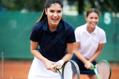 Happy fit people playing tennis together. Sport concept © NDABCREATIVITY