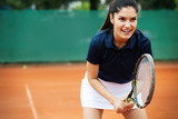 Portrait of forceful woman playing tennis on outdoor tennis court