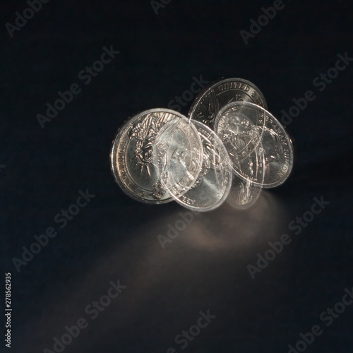 Spinning coin in stroboscopic light on a dark background, close up. One dollar