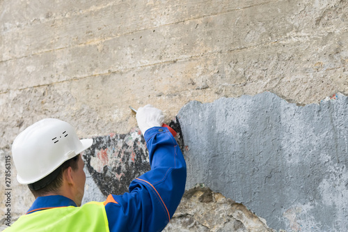 Foto a man in a helmet clears a wall of forbidden inscriptions, view from the back
