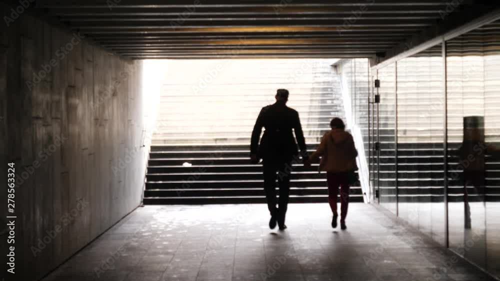 Dark underpath tunnel people silhouette walking couple man and woman different growth Dark underpath tunnel people silhouette walking couple man and woman different growth