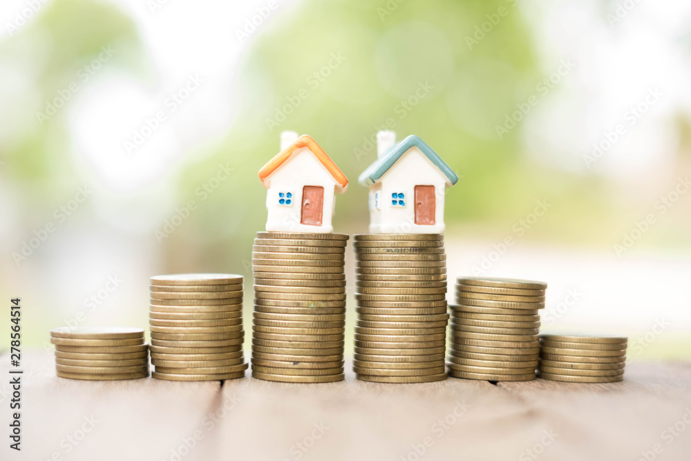  Saving money concept, coin stack growing business, save money for investment. coins to buy a home concept concept for property ladder. A small house on a pile of coins And have a financial chart.