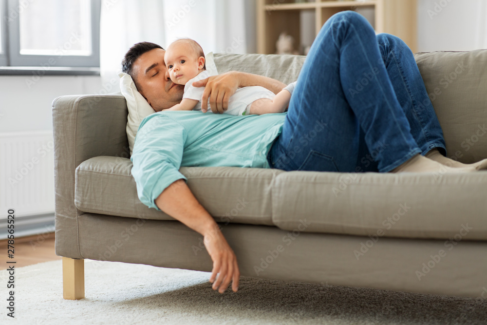 family, parenthood and fatherhood concept - middle aged father with little baby daughter sleeping on sofa at home
