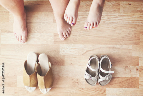 Mother and daughter sitting in the living room at home. Top view of barefoot legs and shoes on the barefoot feets and empty copy space for Editor's text.