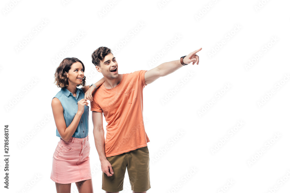 Fototapeta premium cheerful man looking away and pointing with finger near smiling woman isolated on white