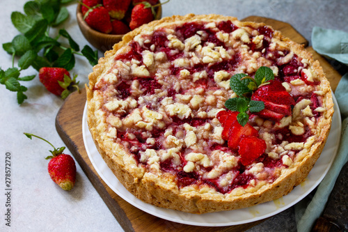 Delicious summer dessert strawberry pie with crumble, sweet delicious holiday cake with strawberry on a light stone or slate table.