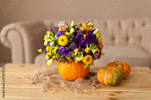 Autumn floral bouquet in a pumpkin vase for Halloween