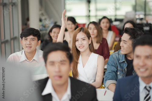 Young asian woman in seminar group raising up hand for asking the speaker in question and answer time in meeting room  woman  have a question in training class. Business seminar and training concept.
