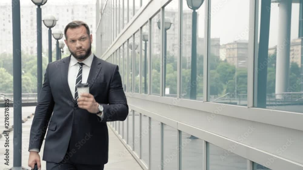 Business man with coffee walking near the office building Business man with coffee walking near the office building