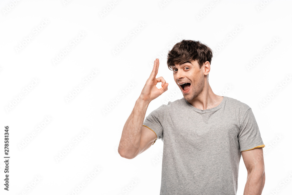 cheerful young man showing ok gesture while smiling at camera isolated on white cheerful young man showing ok gesture while smiling at camera isolated on white