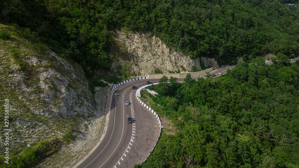 Drones Eye View - winding road from the high mountain pass in Sochi, Russia. Great road trip trough the dense woods. Drones Eye View - winding road from the high mountain pass in Sochi, Russia. Great road trip trough the dense woods.