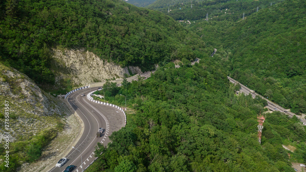 Drones Eye View - winding road from the high mountain pass in Sochi, Russia. Great road trip trough the dense woods.