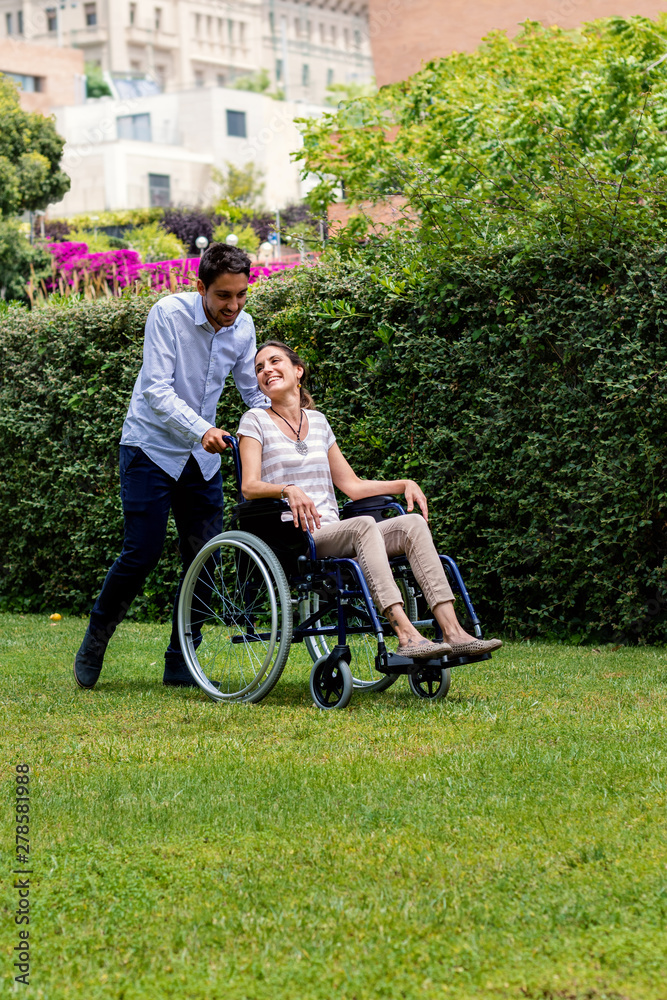 Young man spending time in park with disabled girlfriend. Young man spending time in park with disabled girlfriend.