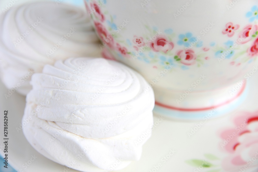  White marshmallow on the background of dishes with a delicate floral print.