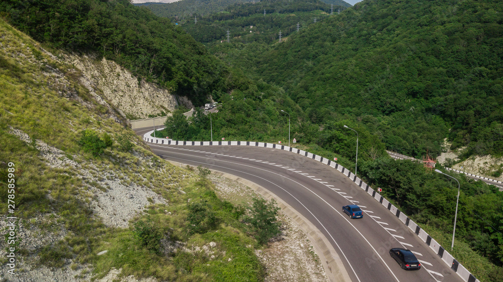 Birds Eye View - winding road from the high mountain pass in Sochi, Russia. Great road trip trough the dense woods.