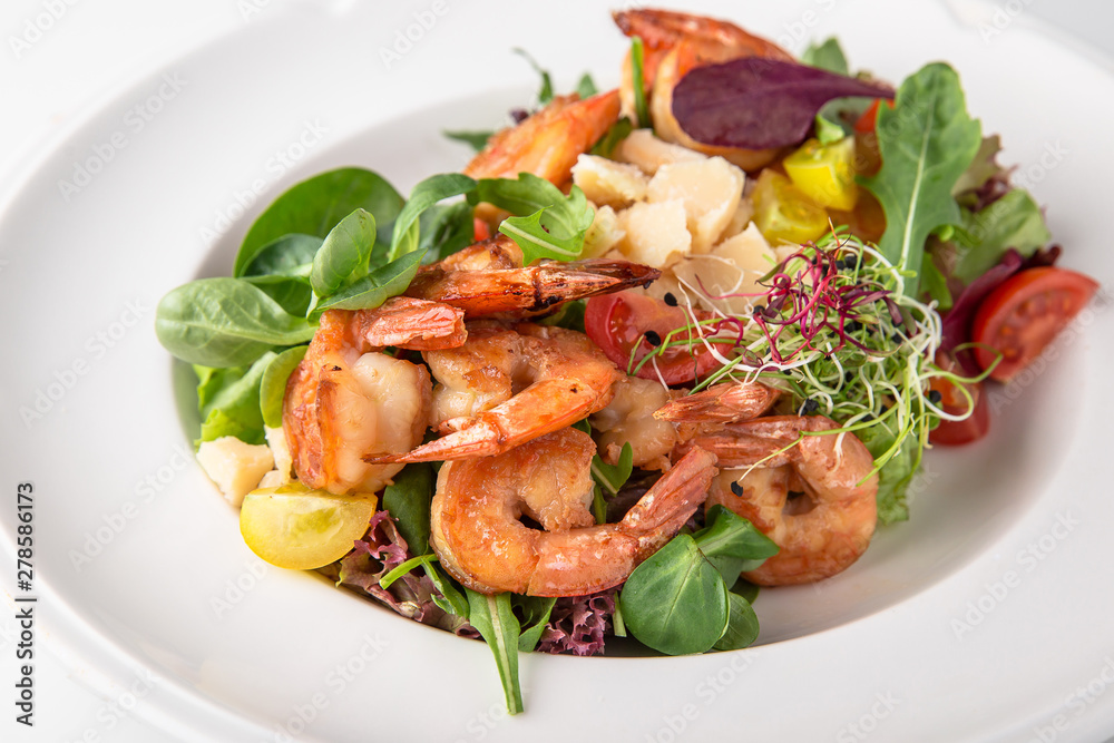 Luxurious seafood salad with grilled king prawns, fish, parmesan cheese, greens and vegetables. Banquet festive dishes. Fine dining restaurant menu. White background. Luxurious seafood salad with grilled king prawns, fish, parmesan cheese, greens and vegetables. Banquet festive dishes. Fine dining restaurant menu. White background.