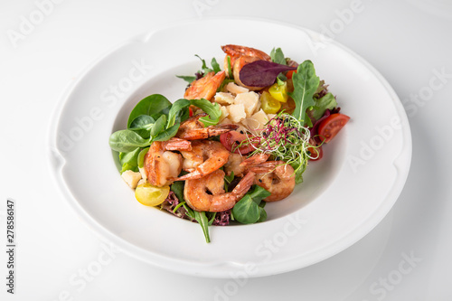 Luxurious seafood salad with grilled king prawns, fish, parmesan cheese, greens and vegetables. Banquet festive dishes. Fine dining restaurant menu. White background.