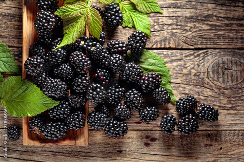 Ripe juicy blackberries with leaves on a wooden table. photo