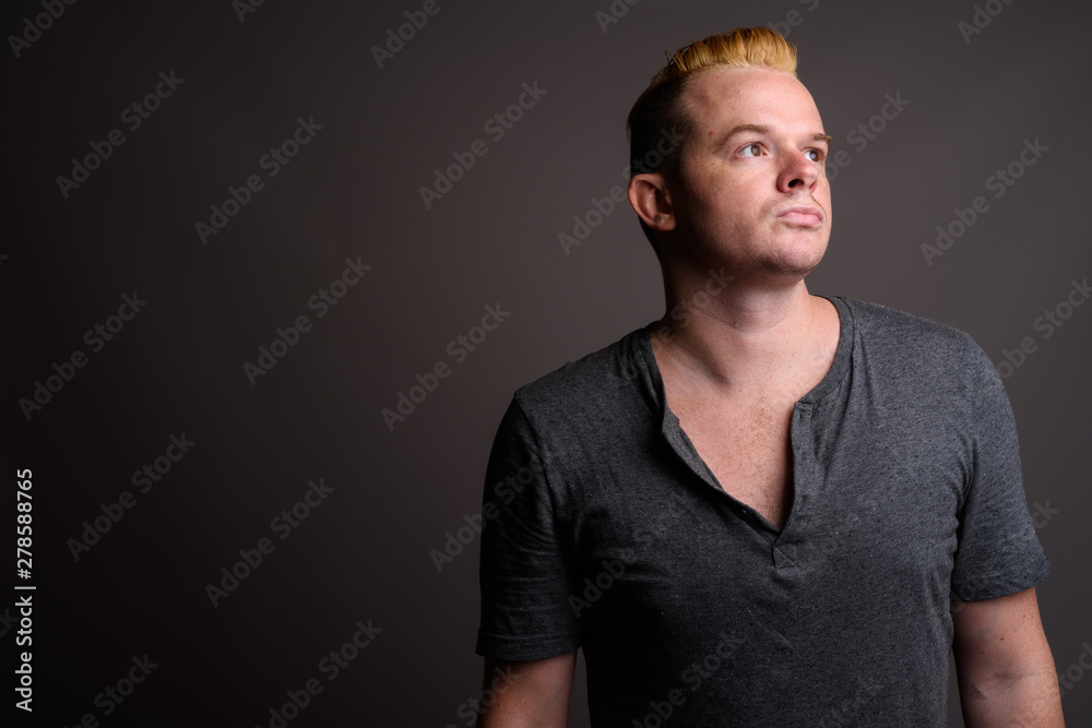 Man with Mohawk hairstyle and blond hair against gray background