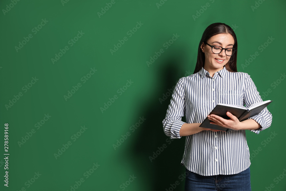 Portrait of young teacher with book on green background. Space for text Portrait of young teacher with book on green background. Space for text