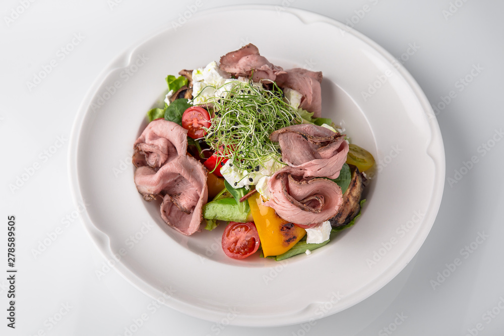 Salad of ham, prosciutto, pork or beef with vegetables, greens, berries and sauce. Nutritious, healthy dish. Banquet festive dishes. Gourmet restaurant menu. White background.