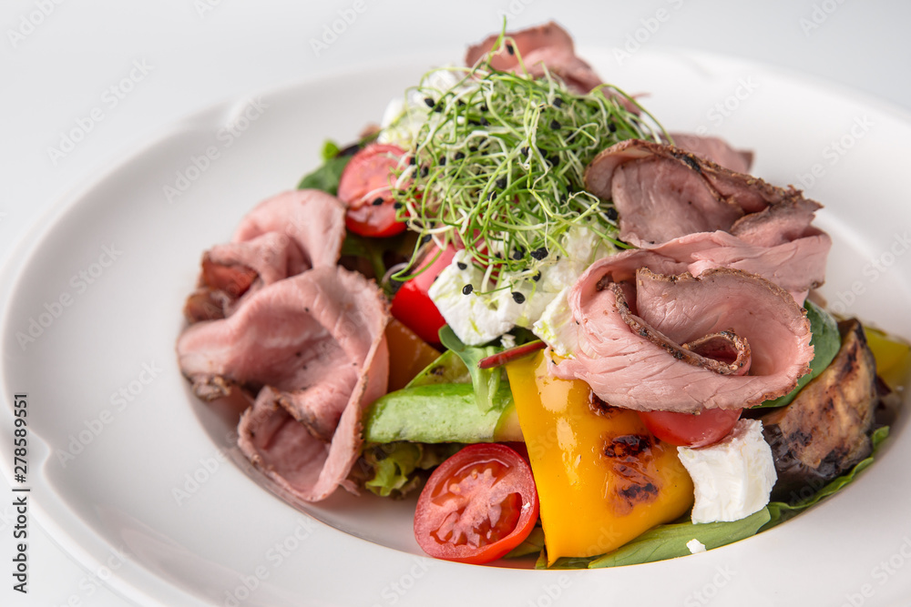 Salad of ham, prosciutto, pork or beef with vegetables, greens, berries and sauce. Nutritious, healthy dish. Banquet festive dishes. Gourmet restaurant menu. White background. Salad of ham, prosciutto, pork or beef with vegetables, greens, berries and sauce. Nutritious, healthy dish. Banquet festive dishes. Gourmet restaurant menu. White background.