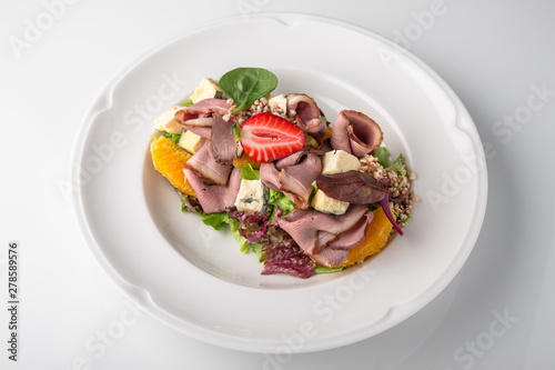Salad of ham, prosciutto, pork or beef with vegetables, greens, berries and sauce. Nutritious, healthy dish. Banquet festive dishes. Gourmet restaurant menu. White background.