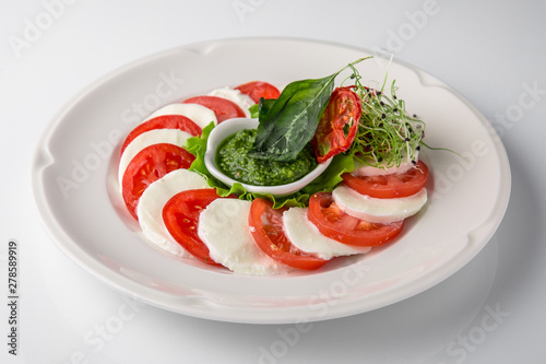 Traditional caprese of tomatoes, mozzarella and pesto sauce. Nutritious healthy dish. Banquet festive dishes. Gourmet restaurant menu. White background.