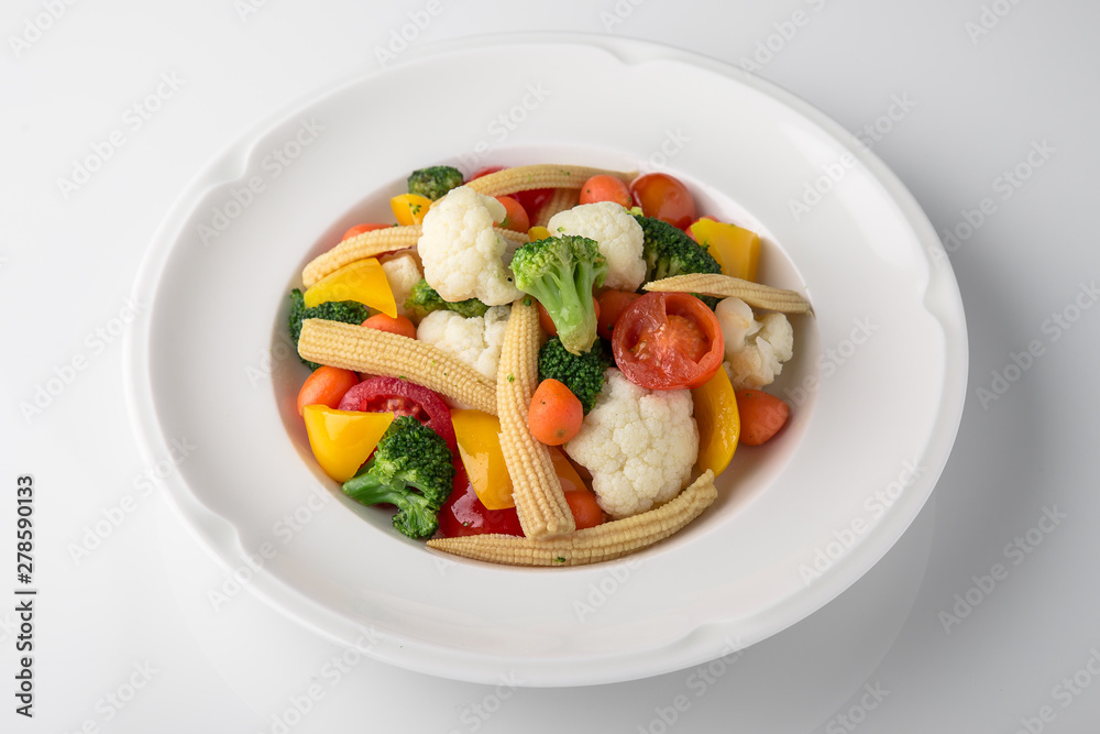 Fresh boiled vegetables: baby carrots, small corn dill, broccoli, cherry tomatoes, sweet peppers. Nutritious healthy dish. Banquet festive dishes. Gourmet restaurant menu. White background. Fresh boiled vegetables: baby carrots, small corn dill, broccoli, cherry tomatoes, sweet peppers. Nutritious healthy dish. Banquet festive dishes. Gourmet restaurant menu. White background.