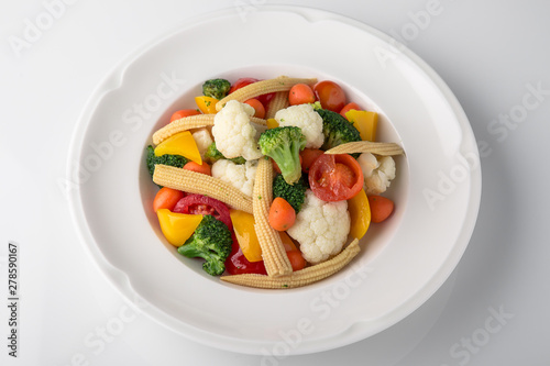 Fresh boiled vegetables: baby carrots, small corn dill, broccoli, cherry tomatoes, sweet peppers. Nutritious healthy dish. Banquet festive dishes. Gourmet restaurant menu. White background.