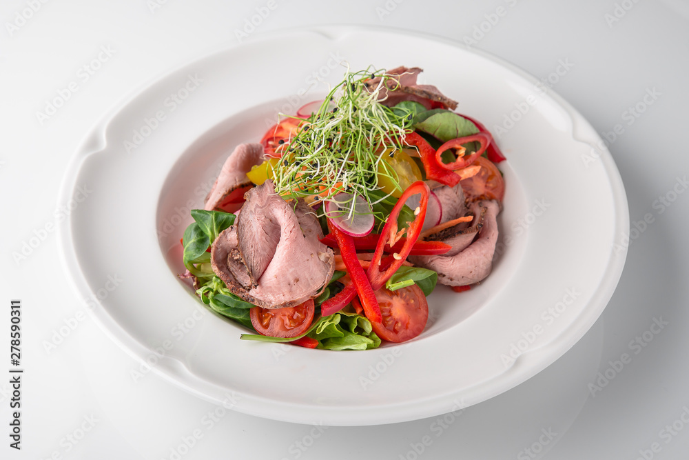 Salad of ham, prosciutto, pork or beef with vegetables, greens, berries and sauce. Nutritious, healthy dish. Banquet festive dishes. Gourmet restaurant menu. White background. Salad of ham, prosciutto, pork or beef with vegetables, greens, berries and sauce. Nutritious, healthy dish. Banquet festive dishes. Gourmet restaurant menu. White background.