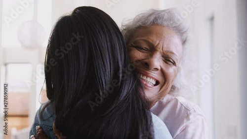 Over The Shoulder View Of Senior Mother Being Hugged By Adult Daughter At Home photo