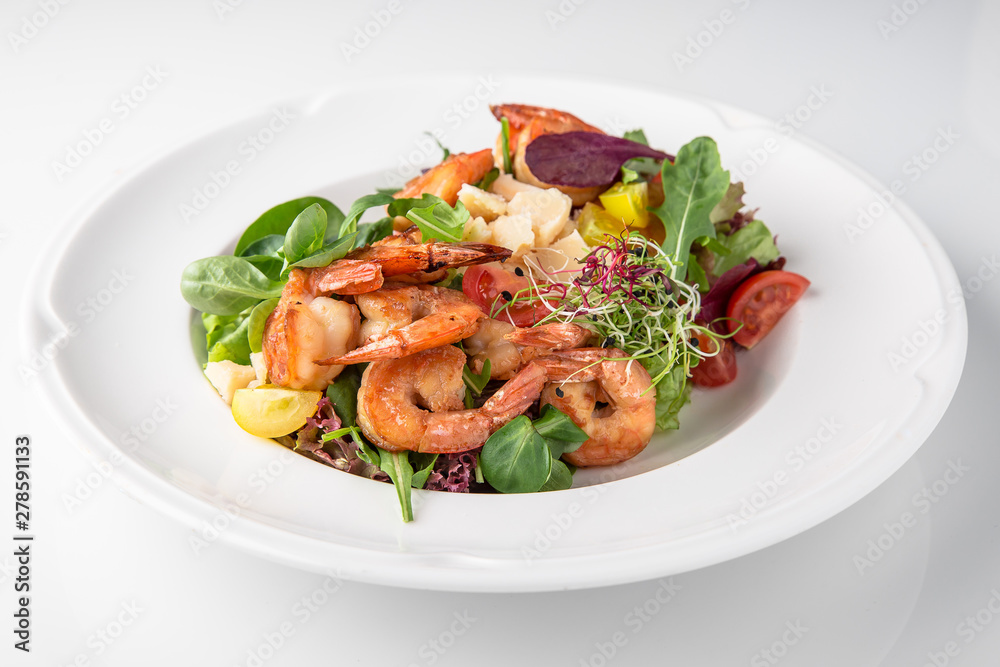 Luxurious seafood salad with grilled king prawns, fish, parmesan cheese, greens and vegetables. Banquet festive dishes. Fine dining restaurant menu. White background. Luxurious seafood salad with grilled king prawns, fish, parmesan cheese, greens and vegetables. Banquet festive dishes. Fine dining restaurant menu. White background.