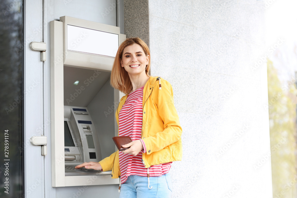 Beautiful woman using cash machine for money withdrawal outdoors. Space for text Beautiful woman using cash machine for money withdrawal outdoors. Space for text