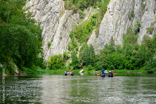 A group of friends in an inflatable raft moving down a river. Mountain river water landscape
