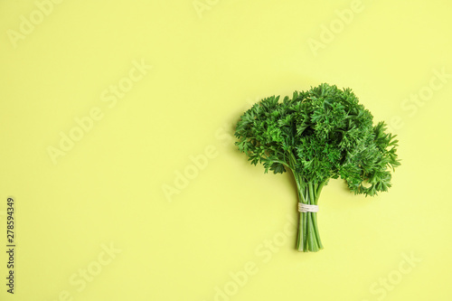 Bunch of fresh green parsley on yellow background, top view. Space for text