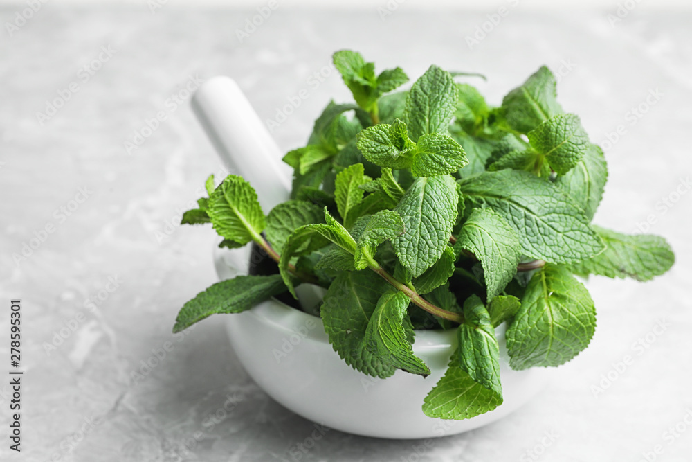 Mortar with fresh green mint and pestle on table