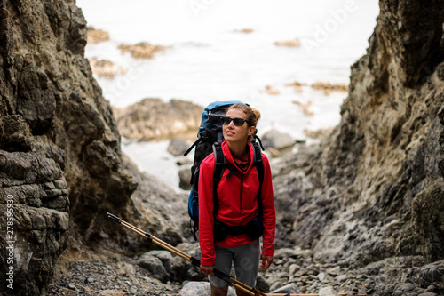 Female hiker with backpack stands between cliffs