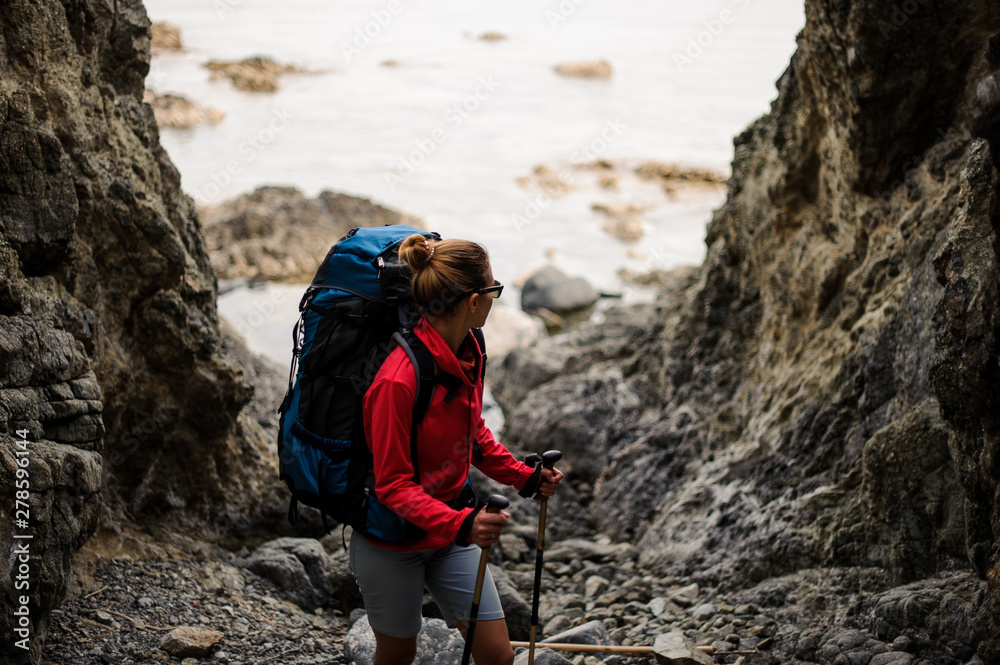 Female hiker with backpack stands between rocks