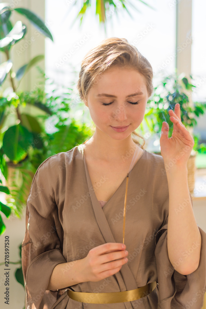 A young beautiful girl holds a smoking aromatic stalk in her hands. Aromatherapy, meditation, healthy life concept. A young beautiful girl holds a smoking aromatic stalk in her hands. Aromatherapy, meditation, healthy life concept.