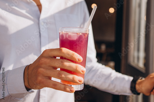 photo of a man's hand holding a glass of cool summer cocktail. A man moves with a lemonade to the summer terrace