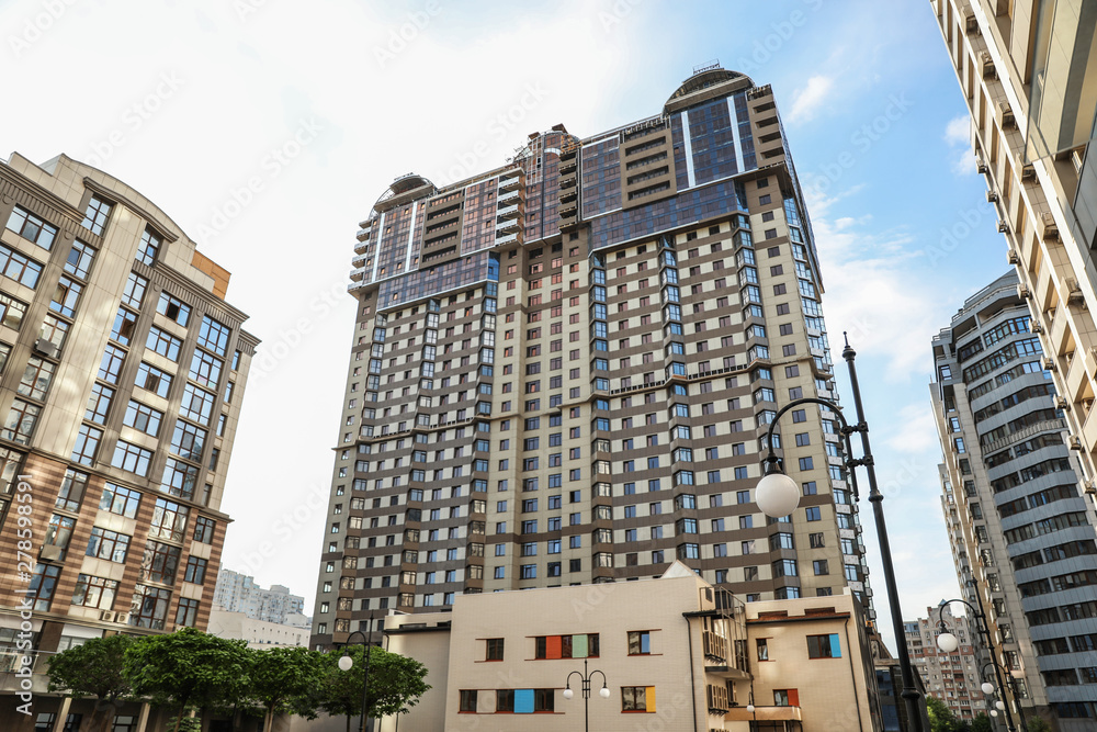 Fototapeta premium Modern buildings with tinted windows against sky. Urban architecture
