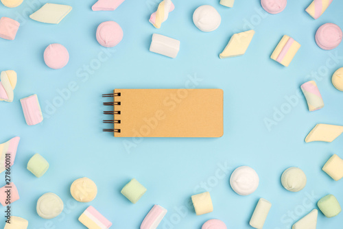 Blue paper background with marshmallow and notepad. Place for your text. Cozy sweet background