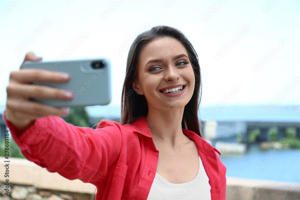 Happy young woman taking selfie on riverside Happy young woman taking selfie on riverside
