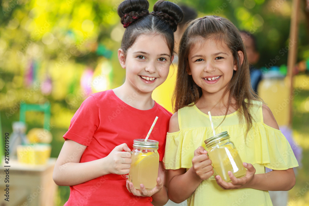 Cute little girls with natural lemonade in park. Summer refreshing drink Cute little girls with natural lemonade in park. Summer refreshing drink