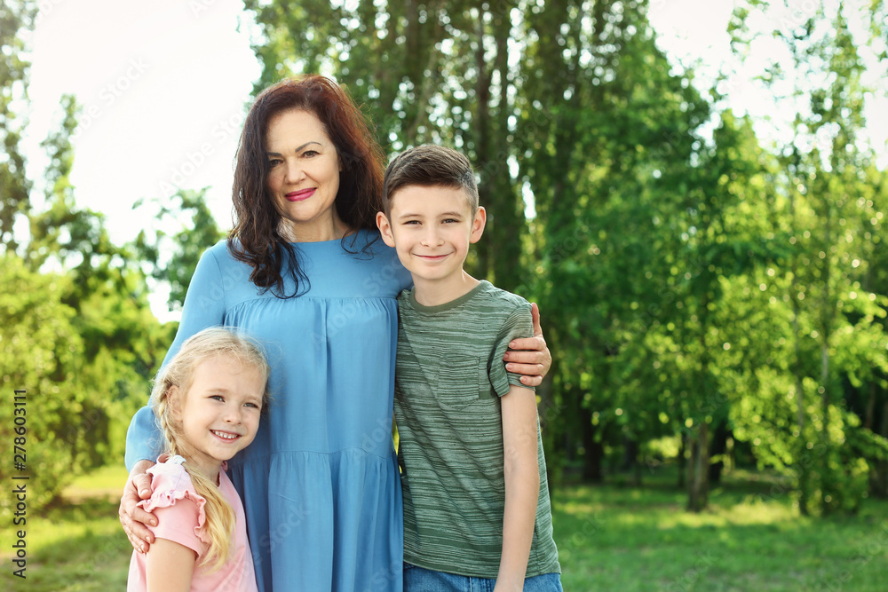 Female pensioner with grandchildren in park. Space for text Female pensioner with grandchildren in park. Space for text