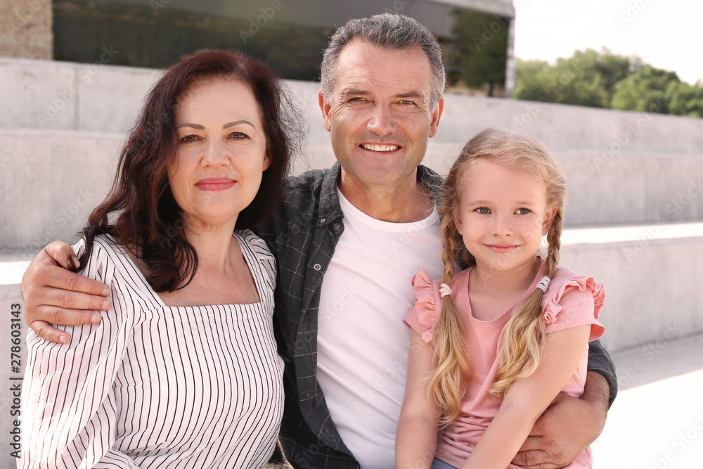 Fototapeta premium Couple of pensioners with granddaughter sitting outdoors