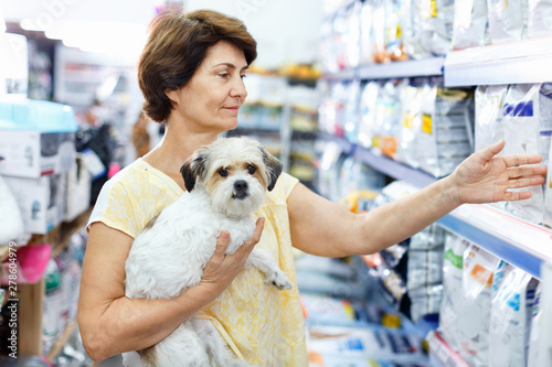 Careful senior woman visiting pet shop in search of dry food for her dog