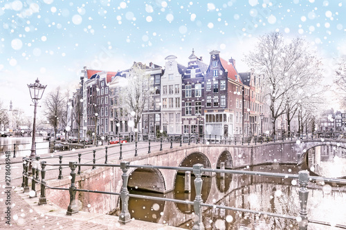 Traditional Dutch old houses and bridges on the canals in Amsterdam on a snowy winter night, The Netherlands photo